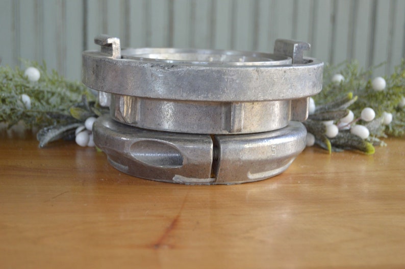 May include: Two silver metal fire hose couplings stacked on top of each other. The top coupling has a small handle on the side. The bottom coupling has a number "5" on the side.