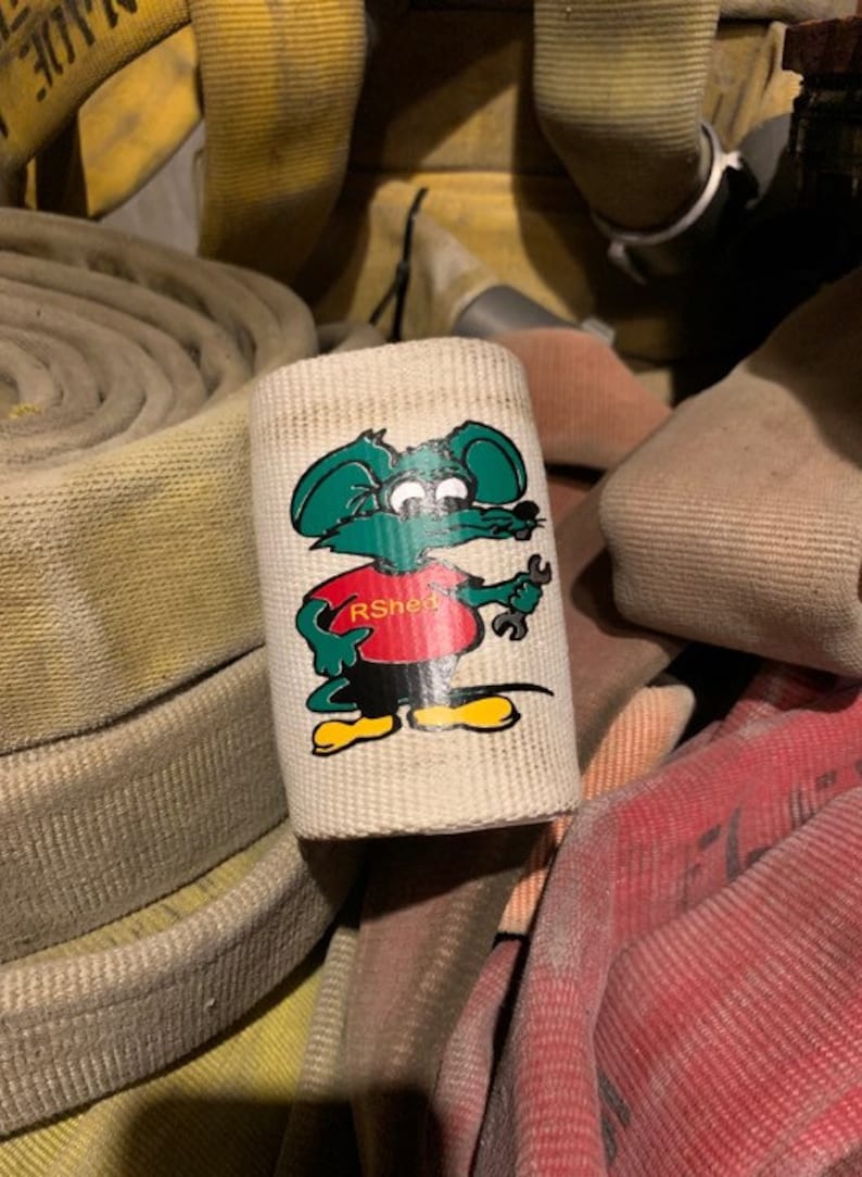 May include: A white canvas fire hose wrap with a cartoon mouse wearing a red shirt with the text "RShee" and holding a wrench. The mouse is green, yellow, and black.