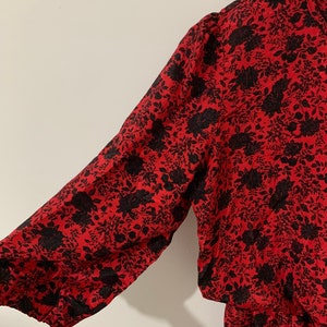 May include: A red and black floral print dress with a long sleeve and a gathered skirt.