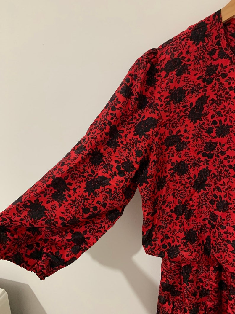 May include: A red and black floral print dress with a long sleeve and a gathered skirt.