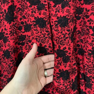 May include: Red and black floral print fabric with a small opening in the center.