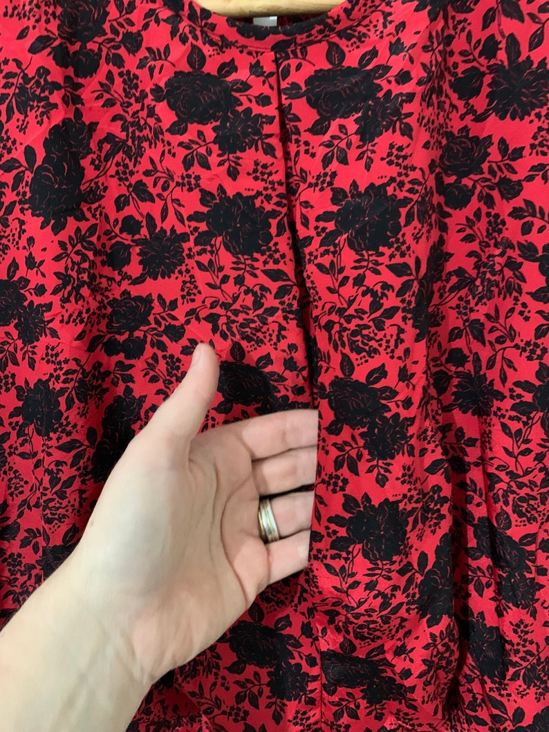 May include: Red and black floral print fabric with a small opening in the center.