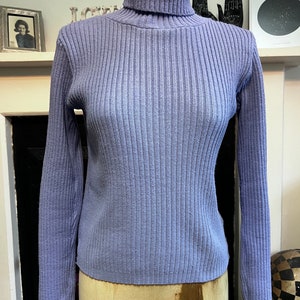May include: A light blue ribbed turtleneck sweater.
