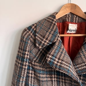 May include: A brown, beige, and teal plaid coat with a wide collar and a single visible dark button. The interior is lined with a solid rust-orange fabric. A white label inside the collar reads "it's a dream" and "Harella" with "made in england".