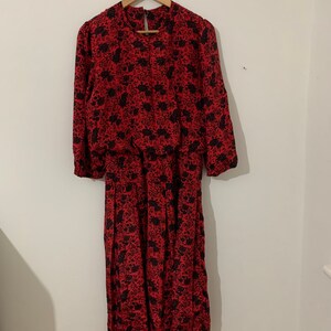 May include: A red and black floral print dress with long sleeves and a gathered waist.