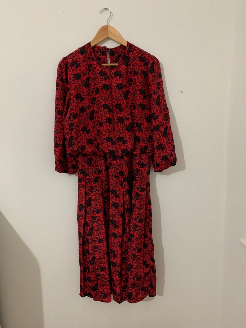 May include: A red and black floral print dress with long sleeves and a gathered waist.