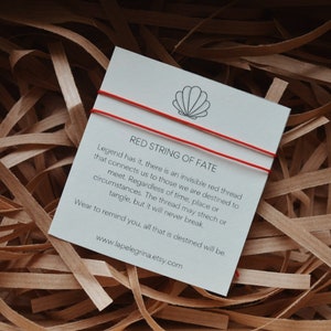Può includere: Braccialetto rosso del destino con un biglietto bianco che recita "La leggenda narra che esiste un filo rosso invisibile che ci collega a coloro con cui siamo destinati a incontrarci. Indipendentemente dal tempo, dal luogo o dalle circostanze. Il filo può allungarsi o aggrovigliarsi, ma non si spezzerà mai. Indossalo per ricordarti che tutto ciò che è destinato sarà. www.lapelegrina.etsy.com"