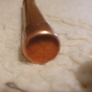 May include: Close-up of the end of a copper pipe, showing the inside of the pipe.