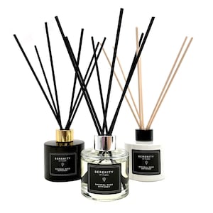 May include: Three glass bottles with black lids and black labels. The bottles are filled with a clear liquid and have black and natural reed diffusers. The labels read "Serenity by Flora Natural Reed Diffuser".
