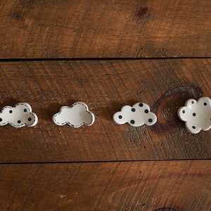 Puede incluir: Cuatro pequeños platos de cerámica blanca en forma de nube con lunares negros. Dos de los platos tienen lunares negros y dos son blancos.