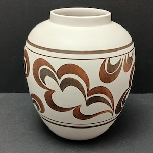May include: A white ceramic vase with a rounded body and a narrow neck. The vase is decorated with brown and dark brown abstract swirl patterns and horizontal bands. The vase is approximately 20 cm tall.