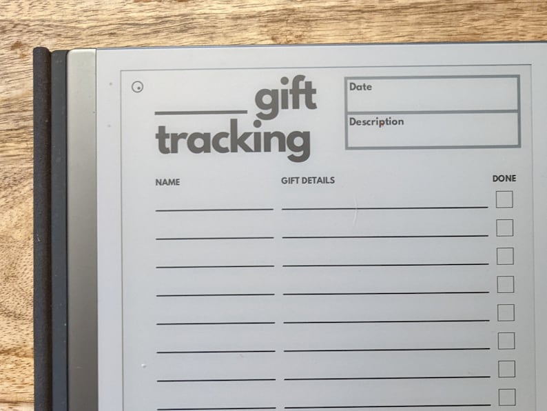 K&ouml;nnte beinhalten: Ein grauer Geschenks-Tracking-Notizblock mit einem schwarzen und silbernen Ordner. Der Notizblock hat einen Bereich f&uuml;r den Namen, das Datum, die Beschreibung, die Geschenkdetails und eine Spalte "erledigt" mit Kontrollk&auml;stchen.
