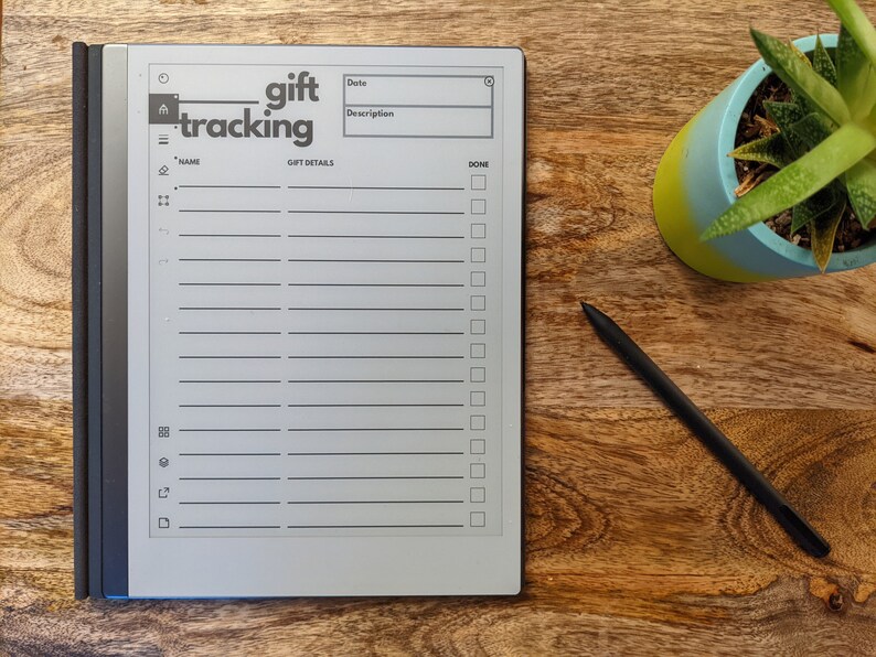 K&ouml;nnte beinhalten: Ein grauer E-Reader mit einem wei&szlig;en Bildschirm, auf dem eine Geschenk-Tracking-Liste angezeigt wird. Die Liste enth&auml;lt Felder f&uuml;r Name, Datum, Beschreibung und ein Kontrollk&auml;stchen f&uuml;r erledigt. Der E-Reader befindet sich auf einer Holzoberfl&auml;che mit einem schwarzen Stift und einer Topfpflanze.