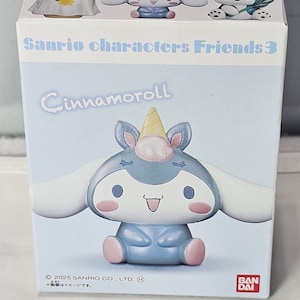 May include: A light blue box featuring a Cinnamoroll figure with a unicorn horn, pink cheeks, and a smiling face. The box reads "Sanrio characters Friends 3" and "Cinnamoroll". The figure is a collectible item.