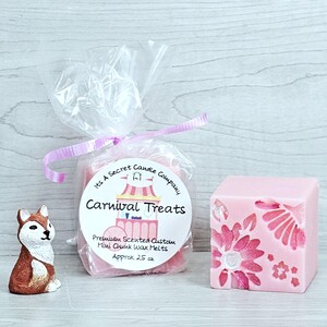 May include: A small brown and white fox figurine, a clear plastic bag containing pink wax melts with a label reading Its A Secret Candle Company Carnival Treats Premium Scented Custom Mini Chunk Wax Melts Approx 25 oz, and a pink wax cube.