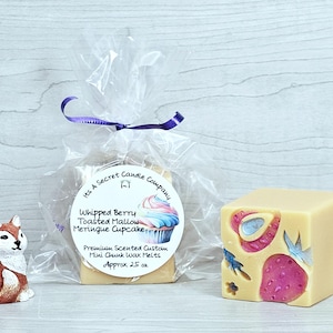 May include: A small fox figurine next to a clear plastic bag containing wax melts with a label reading Its A Secret Candle Company Whipped Berry Toasted Mallow Meringue Cupcake Premium Scented Custom Mini Chunk Wax Melts Approx 25 oz and a cube.