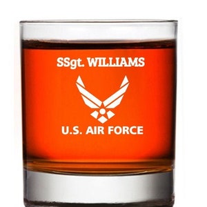 May include: A clear glass tumbler with a personalized inscription that reads "SSgt. WILLIAMS U.S. AIR FORCE". The inscription is in white lettering and features the Air Force emblem.
