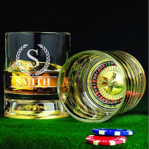 May include: Two clear glass tumblers with a gold rim. One tumbler has a roulette wheel design and the other has a personalized design with the letter "S" and the name "SMITH".
