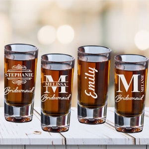 May include: Four clear glass shot glasses with personalised engravings. Each glass has a different name and the word "bridesmaid".