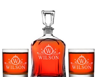 Può includere: Un set di decanter e bicchieri personalizzati. Il decanter e i bicchieri sono in vetro trasparente con un monogramma bianco e il nome "WILSON" inciso su di essi.