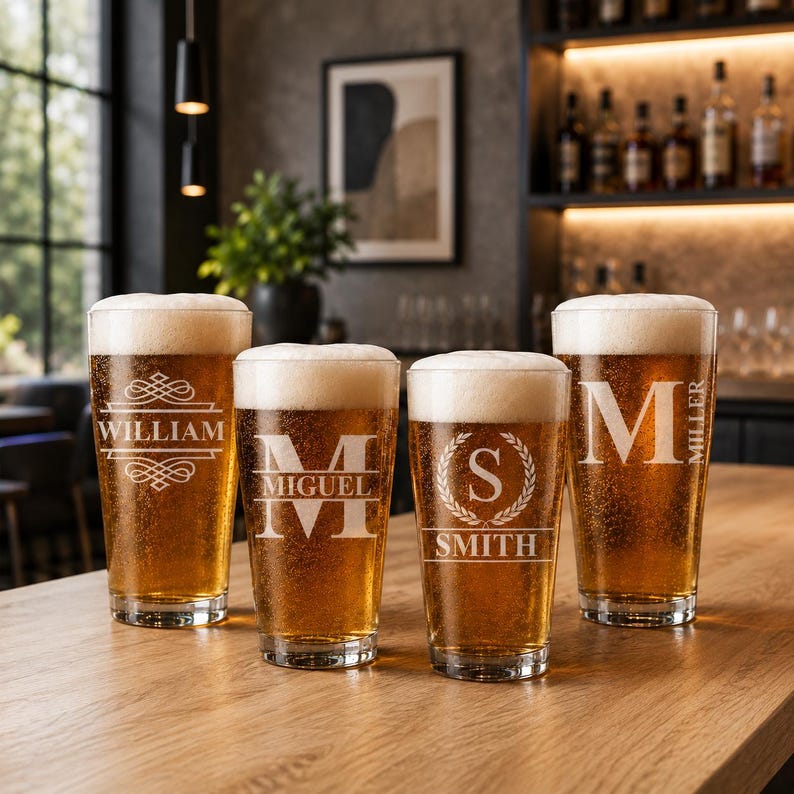May include: Four pint glasses filled with beer and topped with white foam. Each glass is engraved with a name or initial: "WILLIAM", "MIGUEL", "S SMITH", and "M MILLER". The glasses are on a wooden surface.