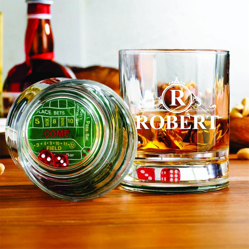 May include: Two clear glass whiskey tumblers with a green felt craps table design on the bottom of one glass. The other glass has a monogrammed "R" for Robert. Both glasses have red dice inside.