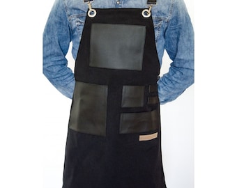 Delantal negro ajustable con bolsillos de cuero, ideal para baristas, barberos y chefs.