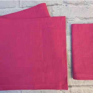 Peut inclure: Deux serviettes en lin rose, une grande et une petite, avec une surface texturée.