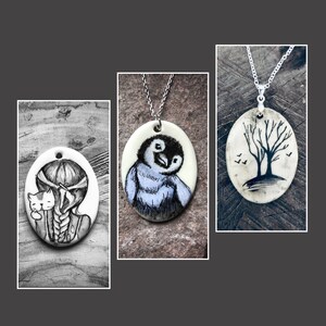 May include: Three oval pendant necklaces. One pendant features a girl with a cat in black and white. Another pendant has a blue and black penguin. The third pendant has a black tree and birds.