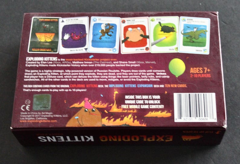 Peut inclure: Dos d'une bo&icirc;te de jeu de cartes Exploding Kittens marron. La bo&icirc;te pr&eacute;sente des illustrations de chats et d'autres personnages sur des cartes. Le texte comprend les d&eacute;tails du jeu, la tranche d'&acirc;ge et la phrase "&Agrave; L'INT&Eacute;RIEUR DE CETTE BO&Icirc;TE SE TROUVE VOTRE CODE UNIQUE POUR D&Eacute;BLOQUER DU CONTENU DE JEU MOBILE GRATUIT !"