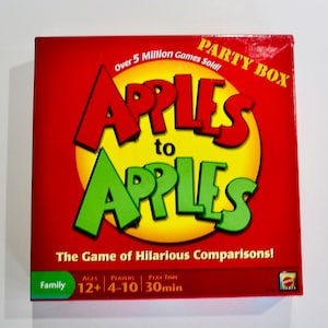 May include: A red box for the party game "Apples to Apples." The game title is in large, colorful letters, with "Apples" in red and green. The box also includes the text "Over 5 Million Games Sold!" and "The Game of Hilarious Comparisons!"