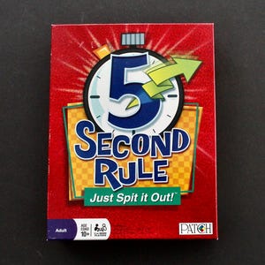 May include: A red game box with the text "5 Second Rule" in blue and white. The box features a timer graphic with a green arrow and the phrase "Just Spit it Out!". The game is for ages 10+ and for 3 or more players.