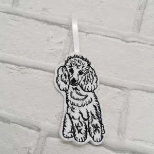 May include: White felt ornament with a black embroidered image of a poodle.