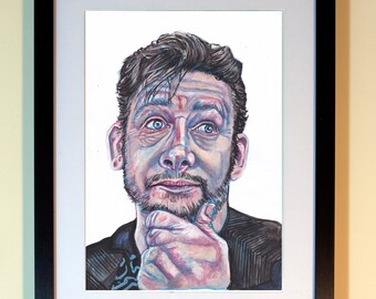 Könnte beinhalten: Gerahmtes Aquarellporträt eines Mannes mit blauen Augen, Bart und dunklem Haar. Das Kunstwerk befindet sich in einem schwarzen Rahmen mit weißem Passepartout. Der Mann berührt sein Kinn mit der Hand.