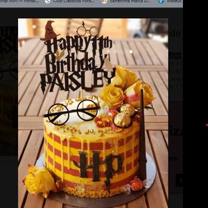 Könnte beinhalten: Ein Geburtstagskuchen mit gelben und roten Streifen, verziert mit gelben Rosen, Pralinen und einem schwarzen Tortenaufsatz mit der Aufschrift "Happy 11th Birthday Paisley". Der Kuchen hat auch eine schwarze Brille und die Buchstaben "HP".