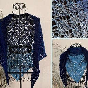 May include: A navy blue and light blue crocheted shawl displayed on a mannequin. The shawl features an open, lacy design with a gradient effect, transitioning from dark to light blue. The intricate pattern is visible, showcasing the craftsmanship.