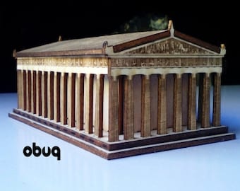 May include: A wooden model of a classical Greek temple, featuring a rectangular structure with numerous vertical columns. The model is constructed from light and dark brown wood, with intricate details on the roof and facade. The word "obuq" is printed in black on the lower left.