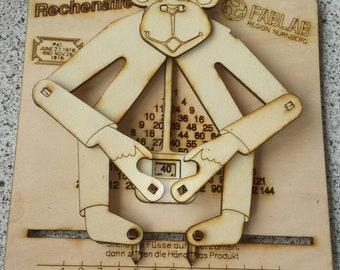 May include: Wooden monkey-shaped educational toy with movable limbs and a number chart. The text "Der Rechenaffe" is at the top, with "FABLAB REGION NÜRNBERG" and patent dates. The monkey's hands point to the number 40.