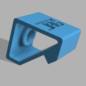 Puede incluir: Una pieza de plástico azul claro impresa en 3D con un agujero roscado y una superficie plana. La pieza tiene un borde redondeado y una forma rectangular.
