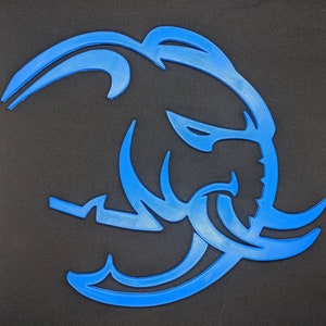Può includere: Una silhouette stilizzata blu di una testa di elefante con un design dettagliato.