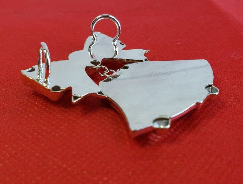 May include: Silver pendant in the shape of a stylized dancing figure. The pendant has a loop at the top for attaching to a chain.
