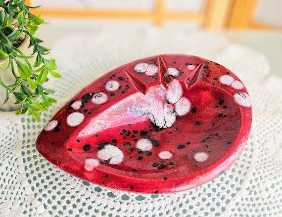 Handmade kidney-shaped atomic-age pottery dish with bold red glaze and white/black spots — pure 1950s Googie aesthetic that doubles as a sculptural trinket dish.