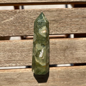 Puede incluir: Una punta de cristal de ágata musgosa verde y blanca con una punta puntiaguda y una superficie lisa y pulida.