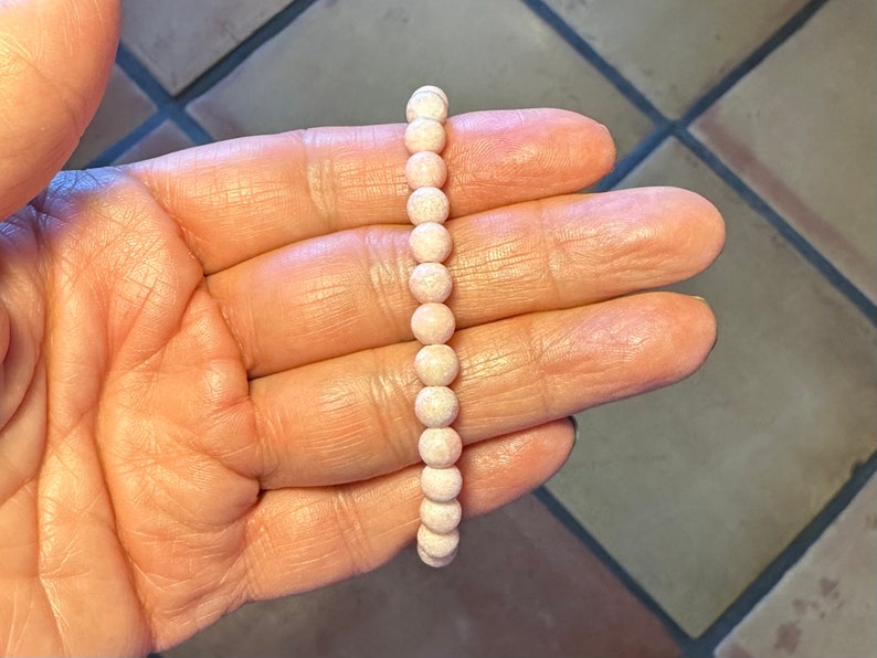 K&ouml;nnte beinhalten: Ein rosa Perlenarmband mit wei&szlig;en Flecken in den Perlen.