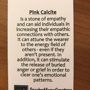 K&ouml;nnte beinhalten: Rosa Calcit-Kristall mit Text, der seine Eigenschaften als Stein der Empathie beschreibt. Der Text besagt, dass er Einzelpersonen dabei helfen kann, ihre empathischen Verbindungen zu anderen zu st&auml;rken. Er kann den Tr&auml;ger auf das Energiefeld anderer abstimmen, selbst wenn diese nicht anwesend sind. Dar&uuml;ber hinaus kann er die Freisetzung von unterdr&uuml;ckter Wut oder Trauer f&ouml;rdern, um die emotionalen Muster einer Person zu kl&auml;ren. Der Text enth&auml;lt auch den Namen "SneakerMamaCreations" und den Satz "handgefertigt mit Liebe".