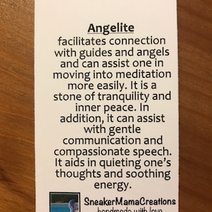 Puede incluir: Una tarjeta blanca con texto negro que describe las propiedades de la angelita, una piedra utilizada en la sanaci&oacute;n con cristales. El texto dice: "La angelita facilita la conexi&oacute;n con gu&iacute;as y &aacute;ngeles y puede ayudar a uno a entrar en meditaci&oacute;n m&aacute;s f&aacute;cilmente. Es una piedra de tranquilidad y paz interior. Adem&aacute;s, puede ayudar con la comunicaci&oacute;n suave y el habla compasiva. Ayuda a calmar los pensamientos y a calmar la energ&iacute;a." La tarjeta tambi&eacute;n incluye el texto "SneakerMamaCreations handmade with love" y una peque&ntilde;a imagen de un cristal azul y morado.