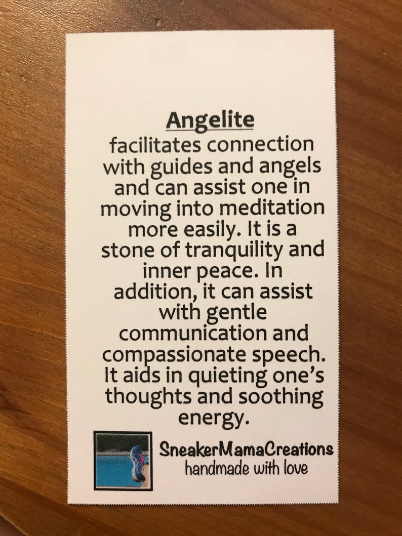 Puede incluir: Una tarjeta blanca con texto negro que describe las propiedades de la angelita, una piedra utilizada en la sanaci&oacute;n con cristales. El texto dice: "La angelita facilita la conexi&oacute;n con gu&iacute;as y &aacute;ngeles y puede ayudar a uno a entrar en meditaci&oacute;n m&aacute;s f&aacute;cilmente. Es una piedra de tranquilidad y paz interior. Adem&aacute;s, puede ayudar con la comunicaci&oacute;n suave y el habla compasiva. Ayuda a calmar los pensamientos y a calmar la energ&iacute;a." La tarjeta tambi&eacute;n incluye el texto "SneakerMamaCreations handmade with love" y una peque&ntilde;a imagen de un cristal azul y morado.