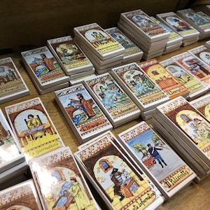 Può includere: Una collezione di piccole piastrelle rettangolari in ceramica con illustrazioni colorate e testo italiano. Ogni piastrella rappresenta una professione diversa, come un giornalista, un avvocato e un'infermiera. Le piastrelle sono disposte in file su una superficie di legno.