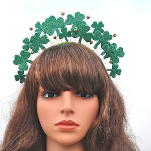 May include: A green shamrock headband with gold glitter accents. The headband is made of felt and has a wire frame. It is perfect for St. Patrick's Day.