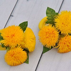 Puede incluir: Dos arreglos de flores de diente de le&oacute;n amarillas con hojas verdes, cada uno atado con una cinta amarilla. Las flores est&aacute;n dispuestas en forma circular.